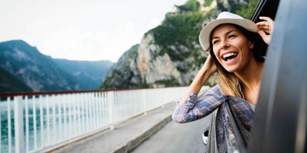 woman-in-car-road-trip-waving-out-the