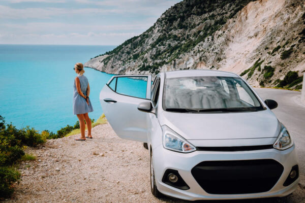 women-near-rented-car-with-open-door-enjoying-myrt